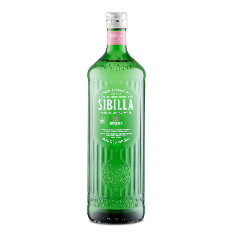 A 1L green glass bottle of Sibilla Italian Still Spring Water features a clear cap and white, green, and pink label displaying the Sibilla brand name and emphasizing its pure, natural mineral spring water origin.