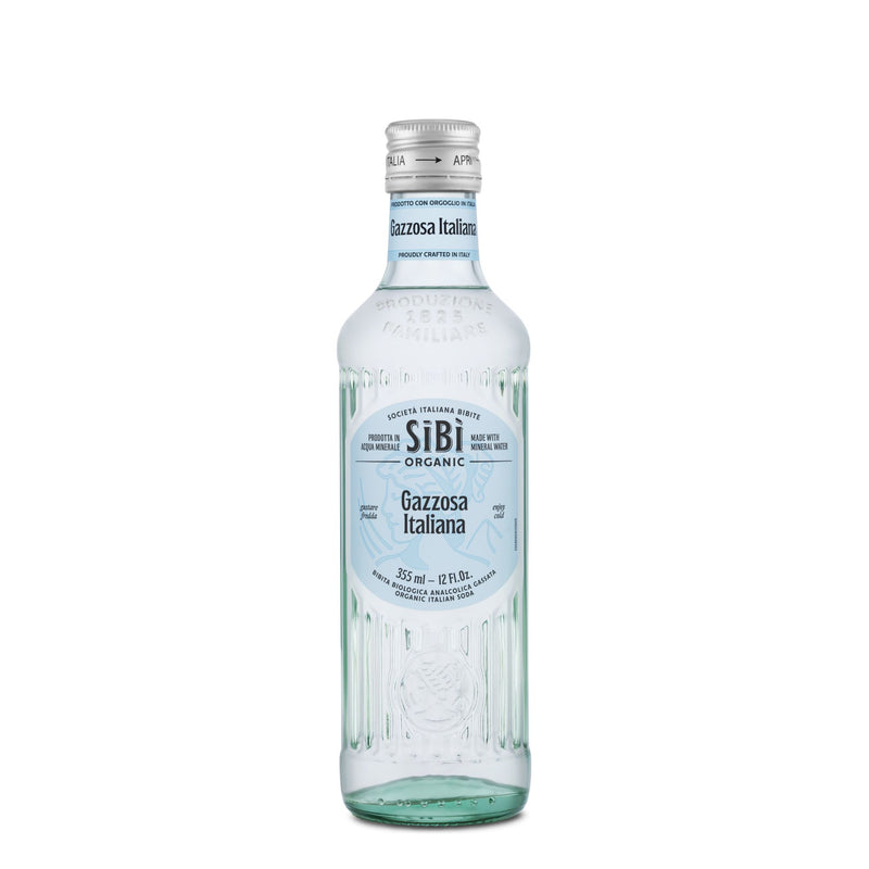A clear 355ml glass bottle of Sibilla Organic Gazzosa Italiana, a refreshing lemon-lime soda with aromatic notes, white and blue Italian label, embossed designs, and a silver cap adorned with blue details.